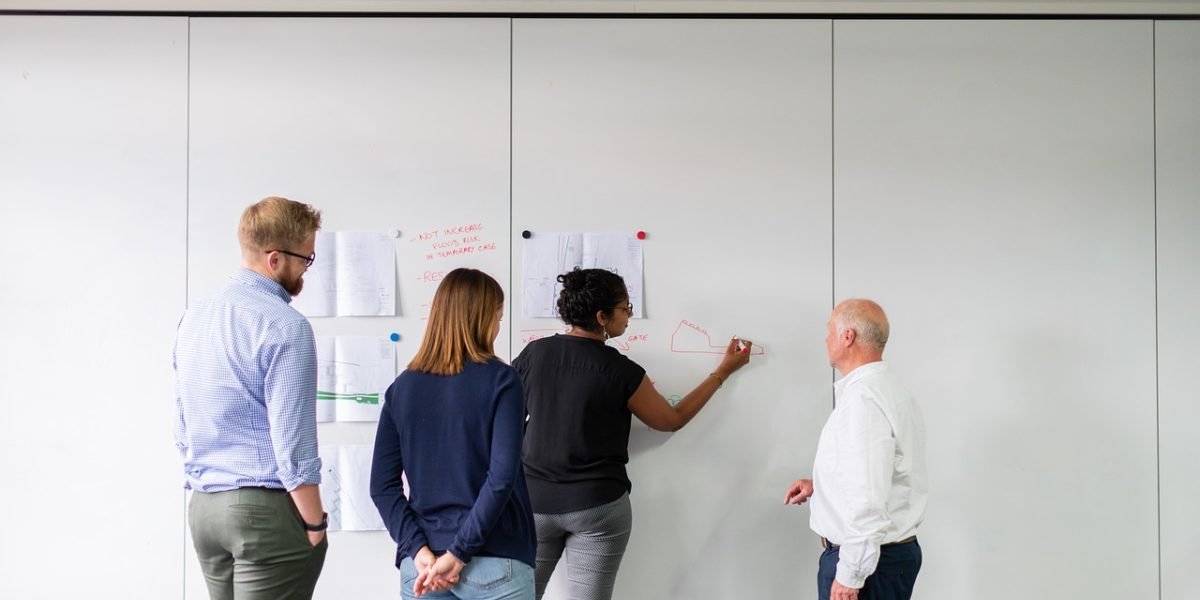 A business team actively discussing solutions and strategy using a whiteboard.