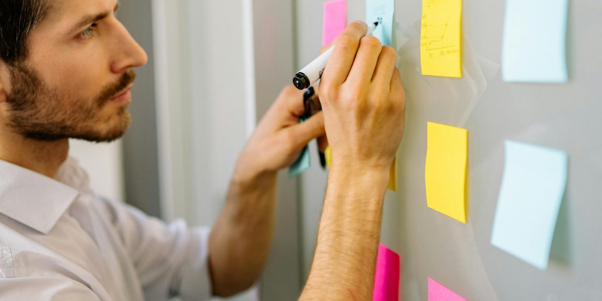 An individual actively organizing and structuring various ideas on a whiteboard.