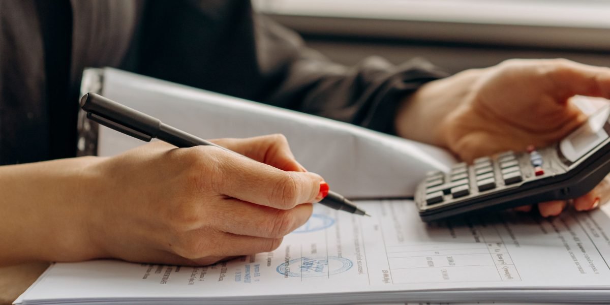 A person carefully reviewing documents and planning their finances for an educational investment.
